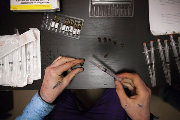 A front-line worker fills syringes with Narcan
