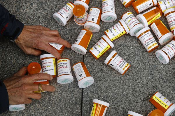 A protester gathers containers that look like OxyContin bottles in 2019 in front of the U.S. Department of Health and Human Services headquarters in Washington